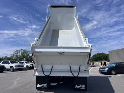 Dump truck bed view showing empty dump body on a 2027 Mack GR64F chassis with a raised tailgate and rear lights.
