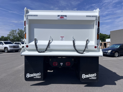 Back of 2027 Mack GR64F dump truck showing dump bed with hooks, rear lights, and Bruckner's mud flaps; VIN 1M2GR4GC3VM057395 visible in listing details.