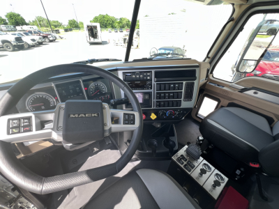 Mack GR64F truck cab interior showing steering wheel, dashboard with gauges, and center console with controls and gear shifter.