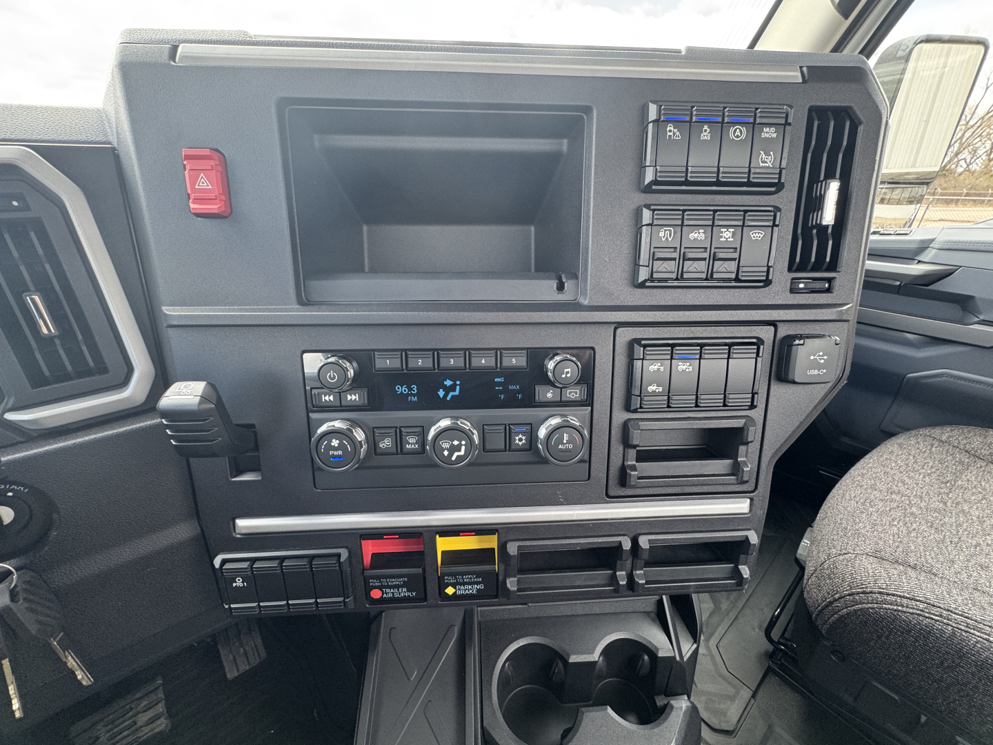 Dashboard of a Mack PR64T truck showing climate controls, radio, switches, and storage compartments.