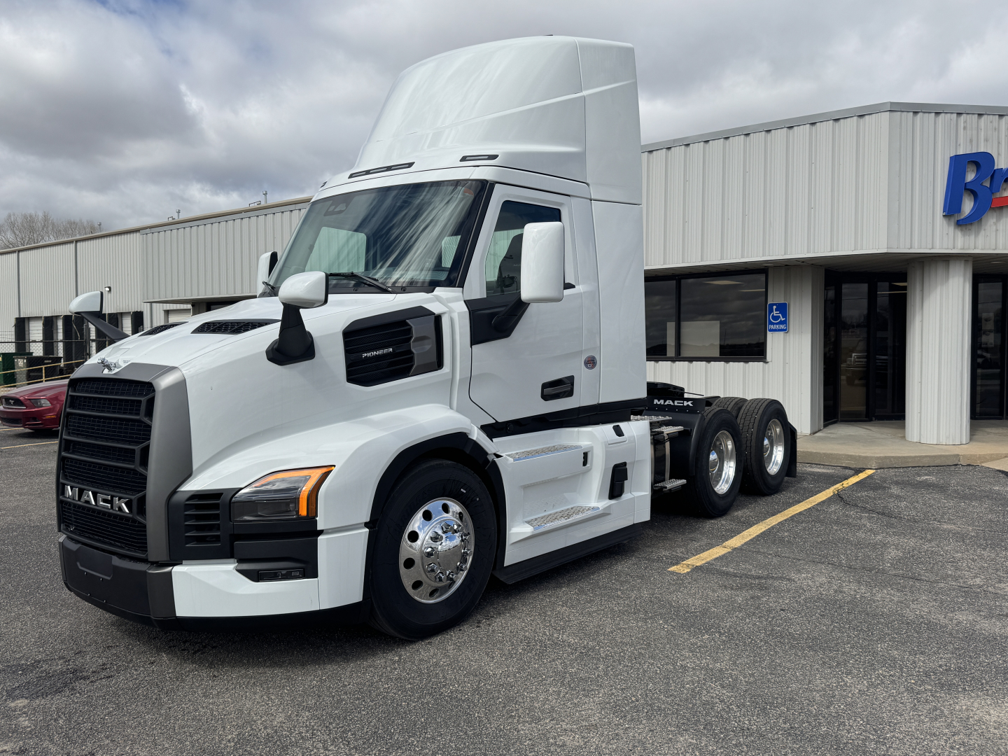 Mack PR64T tractor unit in white, side view showing cab and dual rear axles, front grille with Mack logo, daycab configuration.