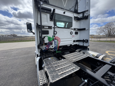 Mack PR64T truck cab interior showing air lines and steps under the sleeper area. Front of cab with chrome steps and coiled colored lines (red, green, blue) near dashboard.