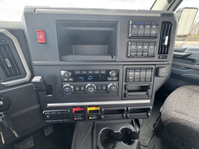 Dashboard of a Mack PR64T truck showing climate controls, radio, switches, and storage compartments.