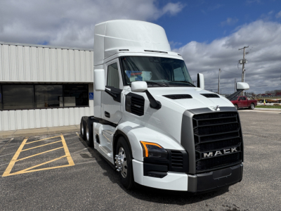 Truck cab showing Mack PR64T badge on grille and side mirrors; front view of white semi-truck with high sleeper cab, large black grille, and headlights.