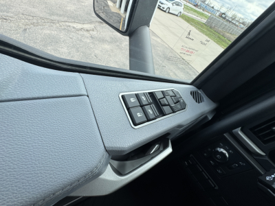 Truck cab interior window controls panel and mirror on Mack PR64T showing door window switch gear and side mirror housing.