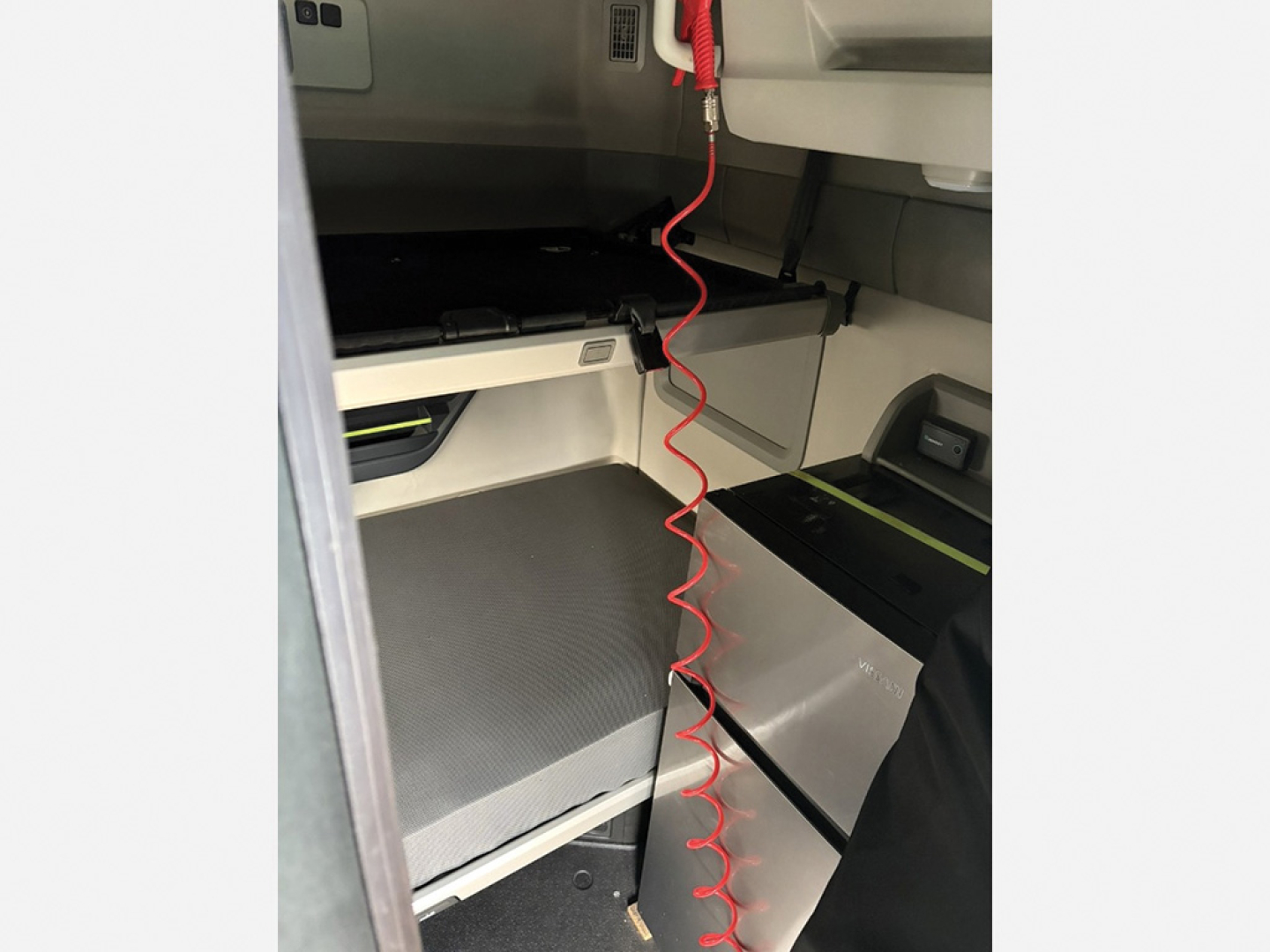 Volvo VNL 840 sleeper cab interior with metallic storage compartments and red coiled air line in foreground.
