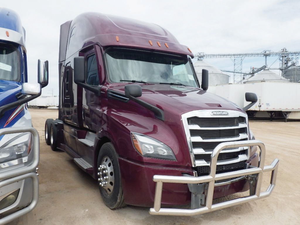  Freightliner Cascadia126 sleeper cab shows maroon exterior with large chrome grille and front bull bar. Left side shows dual rear wheels; other trucks and industrial background.