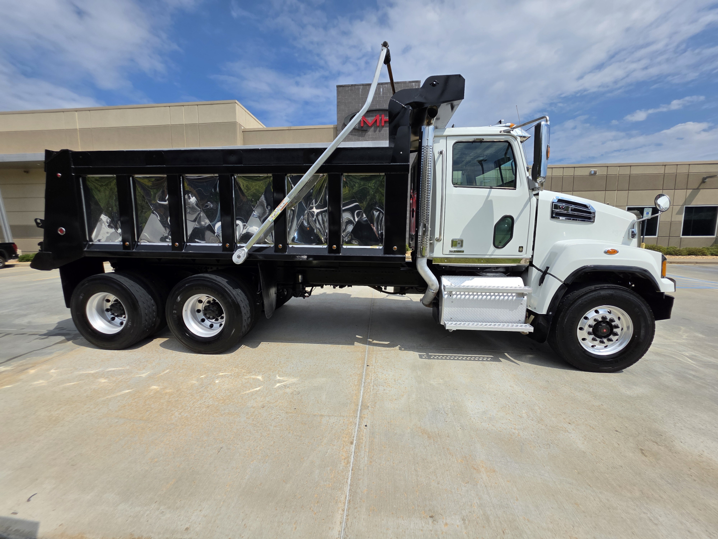Dump truck side view showing 2022 Western Star 4700SF with a black dump bed and crane arm.