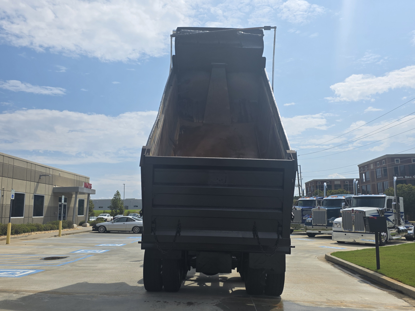Back view of a 2022 Western Star 4700SF dump truck with its bed raised.