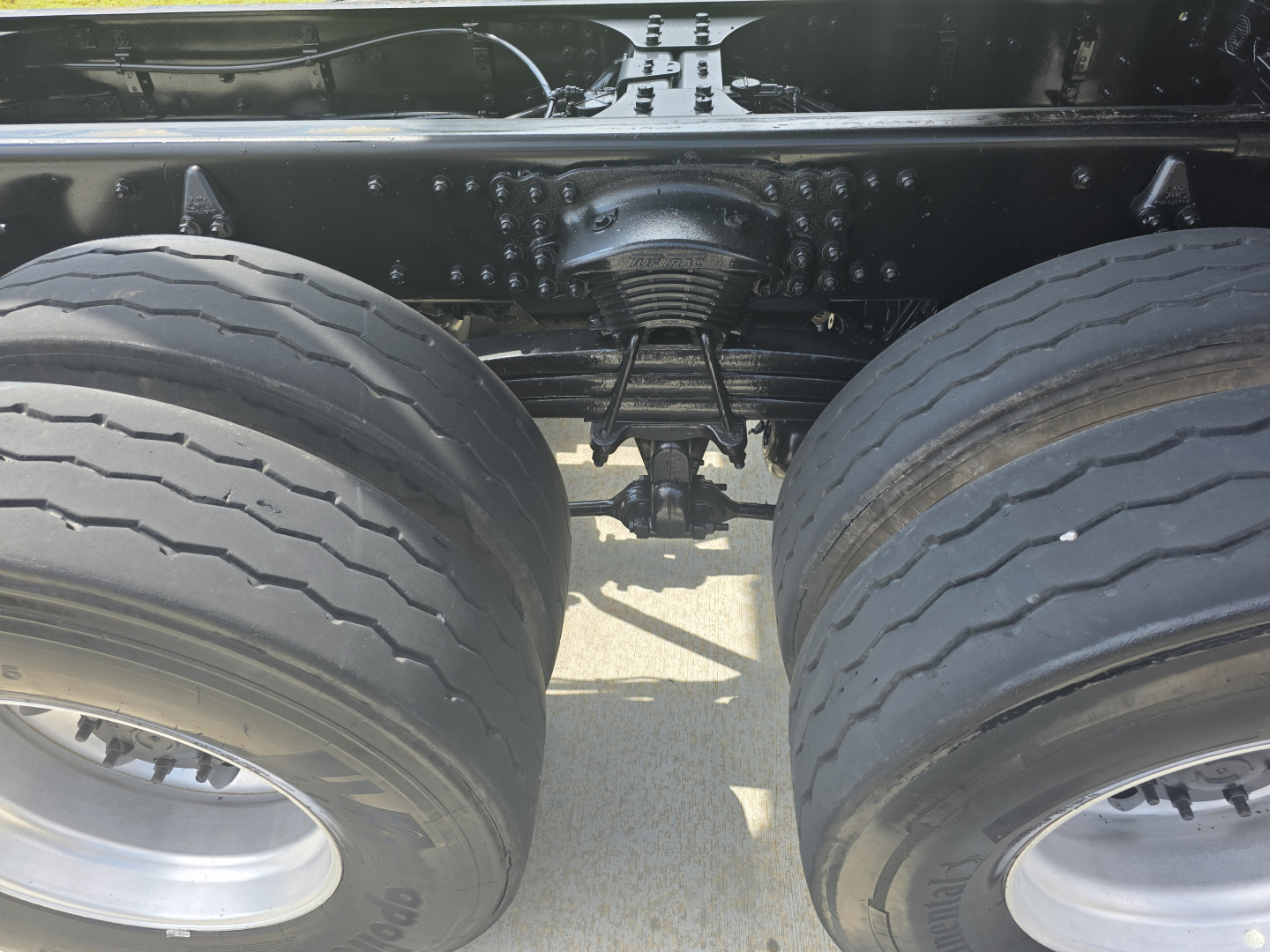 Western Star 4700SF truck rear view showing dual rear axles, suspension, and drivetrain components between the large dual tires.