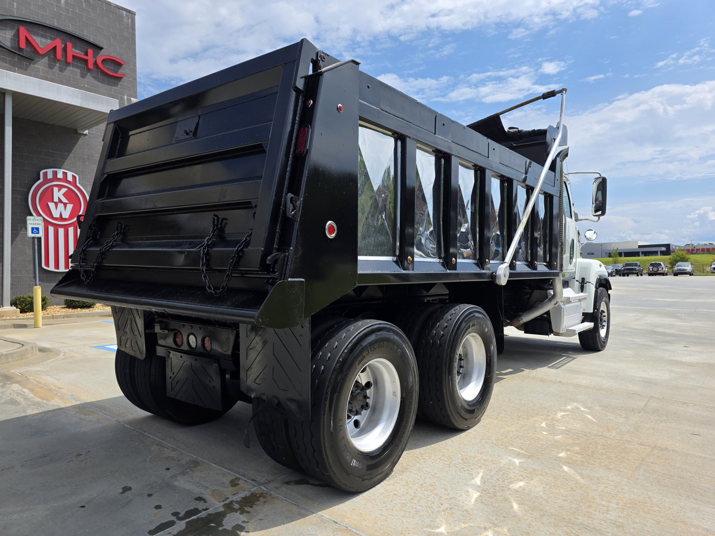 Truck bed of a Western Star 4700SF dump truck viewed from rear-left showing dual rear axles and black dump body.