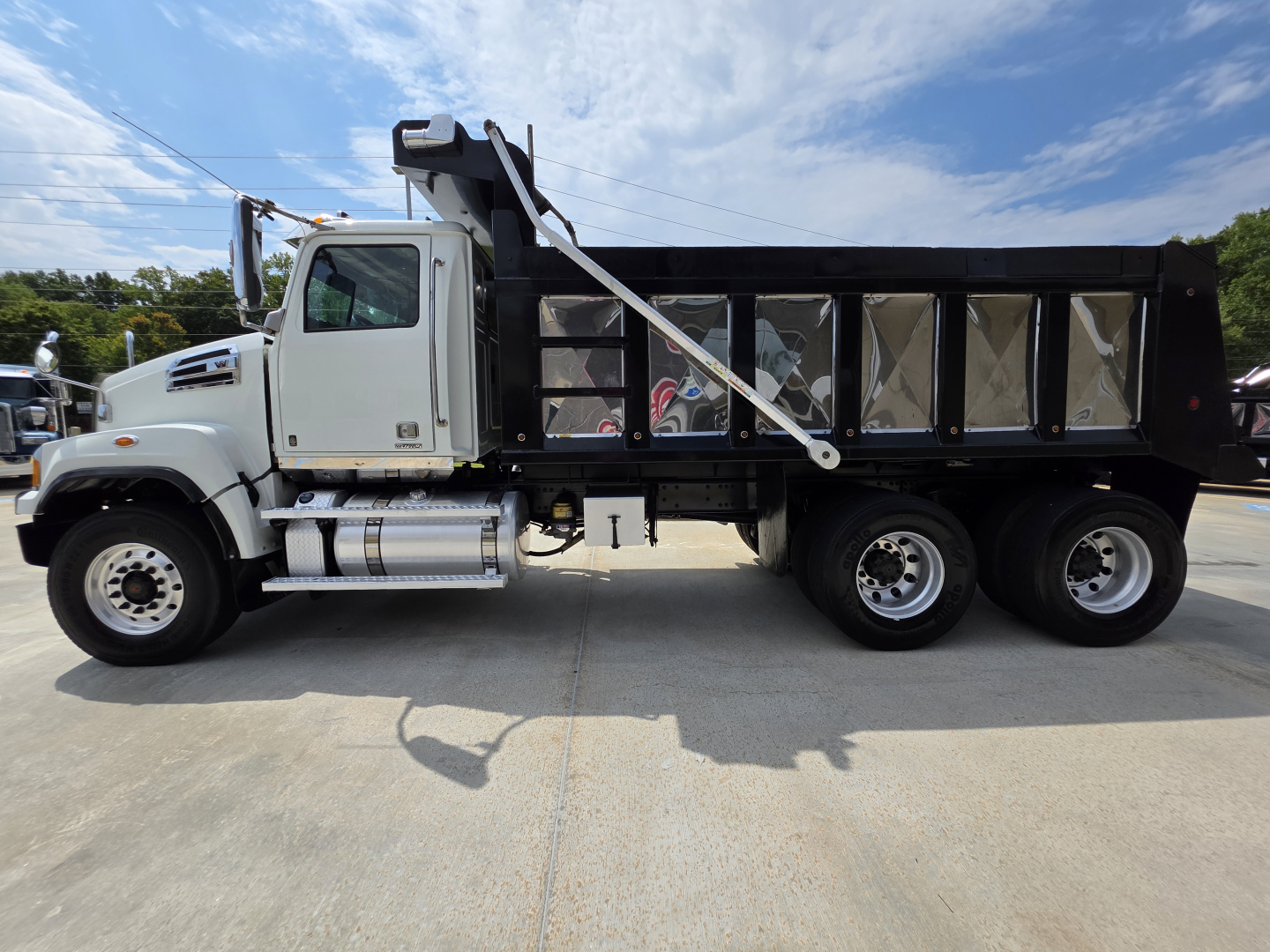 Western Star 4700SF dump truck side view showing black dump body, dual-rear wheels, cab with chrome fuel tanks and steps, VIN 5KKHAVDV5NPNH3553 visible on listing.