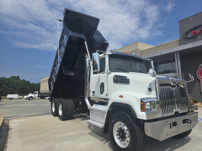 White Western Star 4700SF dump truck with dump bed raised, front grille chrome, side mirrors, and sticker text visible on cab.