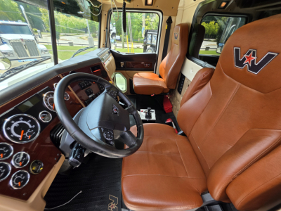 Interior of a 2022 Western Star 4700SF dump truck showing brown leather seats, steering wheel, and dashboard with gauges and controls.