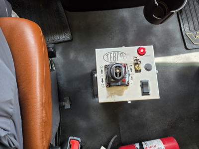Panel with switch and red indicator in truck cab floor area; label shows TERRI? and controls with a central circular component and a red light.