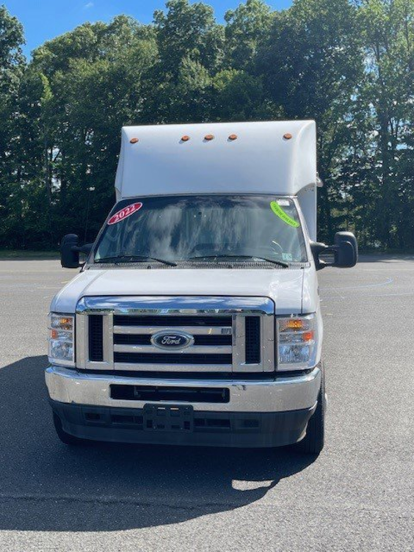 Ford E-Series Cutaway box truck front view showing chrome grille, Ford emblem, windshield with pink and green decals, cargo box topper, and side mirrors.