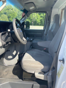 Ford E-Series Cutaway cab interior showing driver and passenger seats, steering wheel, and dashboard in view.