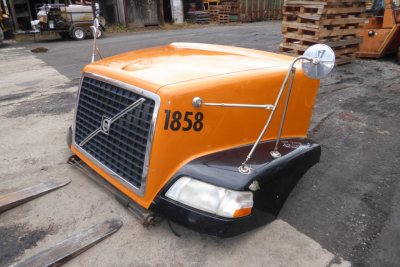 Volvo VNM hood assembly in orange with '1858' number, front grille, headlight, and side mirror visible.