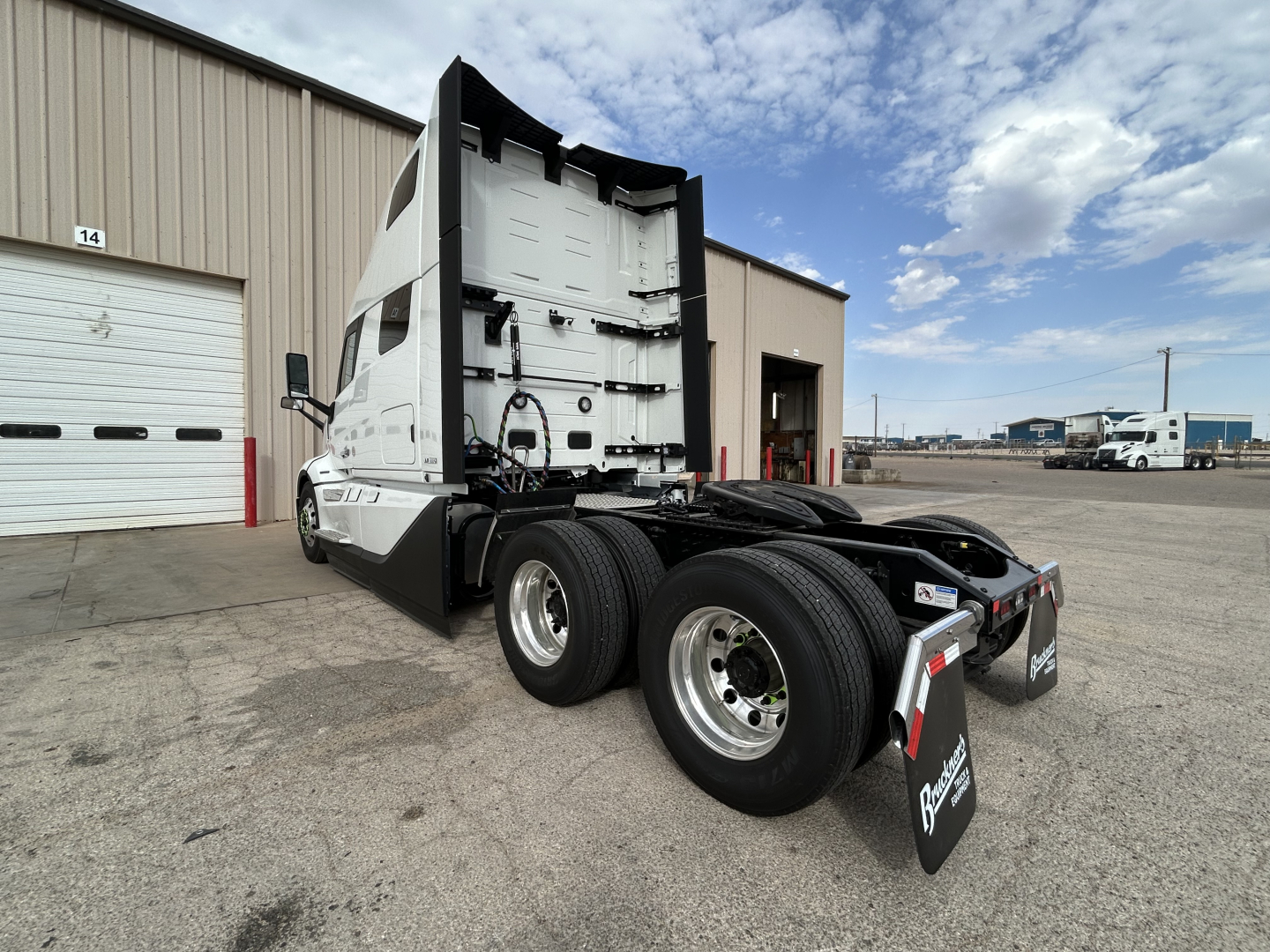 Volvo VNL64T860 truck tractor rear view showing tandem axles and sleeper cab with white exterior and black chassis.