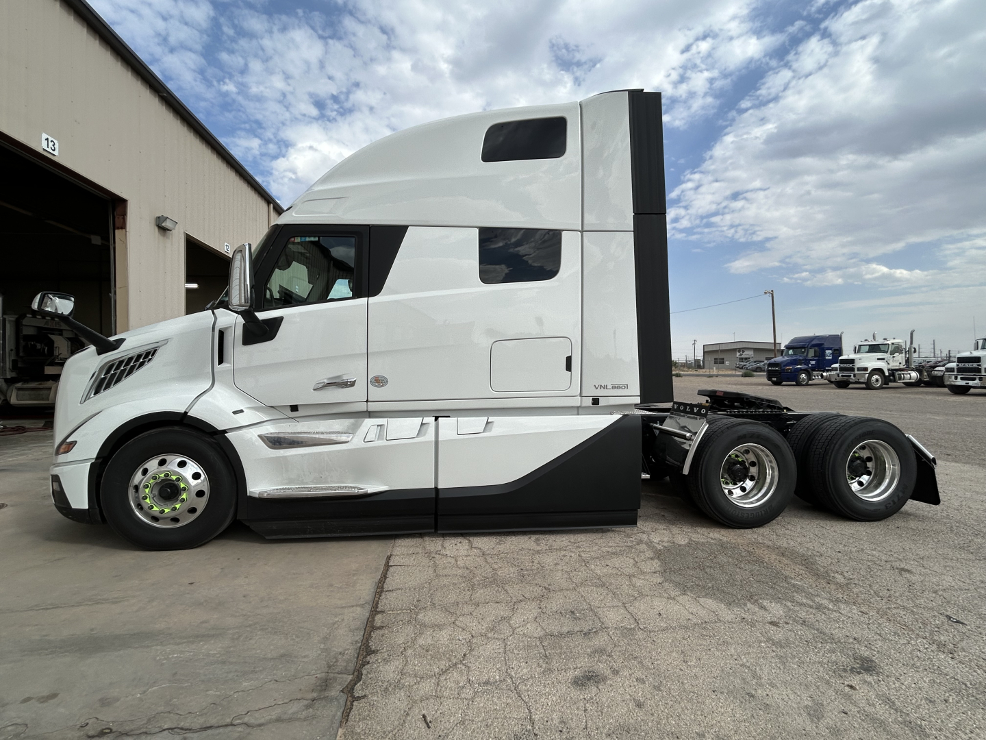 Volvo VNL64T860 truck tractor side view showing sleeper cab and tandem rear wheels with white paint and black accent.