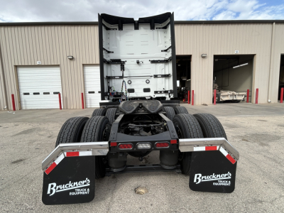 Truck chassis rear view showing fifth wheel and dual rear axles, Volvo VNL cab back, mud flaps with Bruckner’s logo, and surrounding service bay.