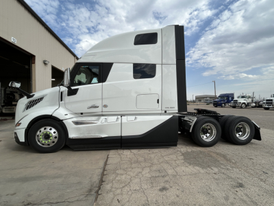 Volvo VNL64T860 truck tractor side view showing sleeper cab and tandem rear wheels with white paint and black accent.