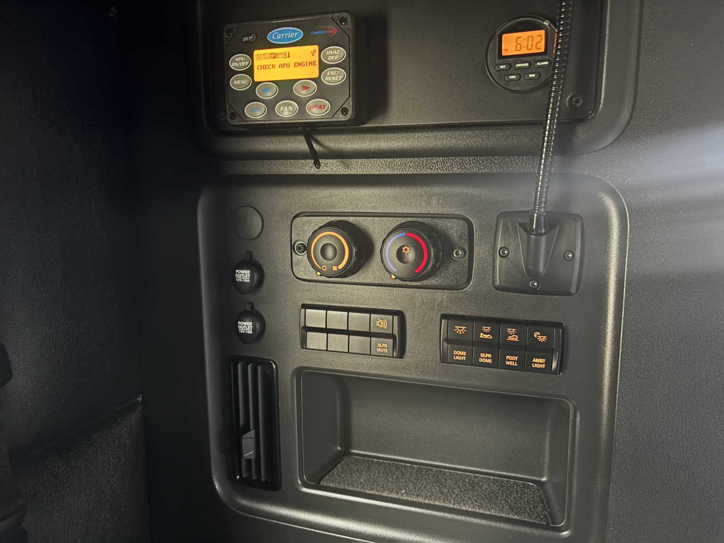 Truck cab interior panel with control dials and digital display. Close-up of dashboard controls, knobs, and a small orange timer display.