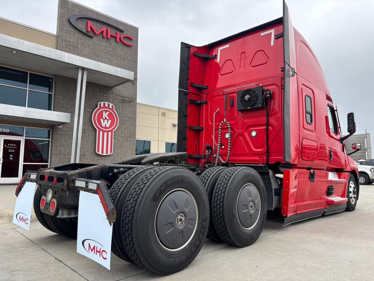 Freightliner PT126064ST conventional sleeper tractor rear and side view showing red cab, dual rear axles, and fifth-wheel area.
