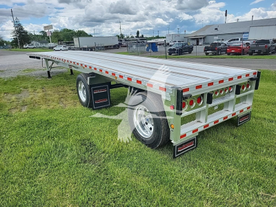 Flatbed trailer with aluminum deck and rear underride guard, dual rear lights and reflective orange-and-white marking tape in a parking lot.