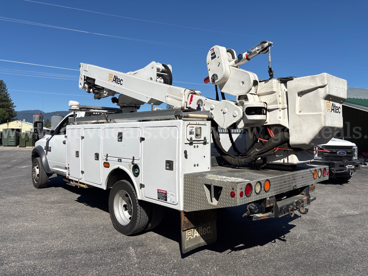 Dodge Ram 5500 bucket truck with rear-mounted Atec articulating boom and service compartments, viewed from the left-rear side.