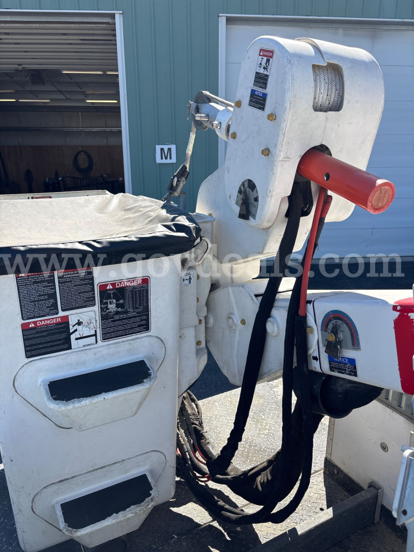 Dodge Ram 5500 bucket truck with hydraulic boom arm and controls, white body, red booster, and warning labels visible.