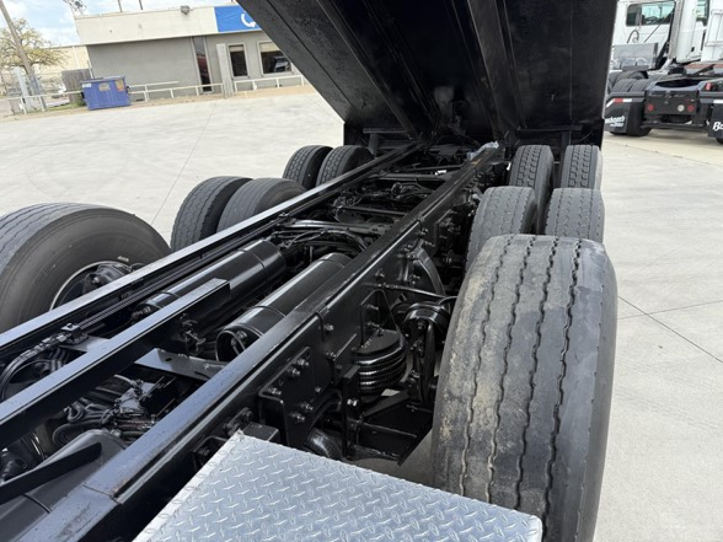 Freightliner 122SD chassis with raised dump bed showing dual rear axles and hydraulic frame components.