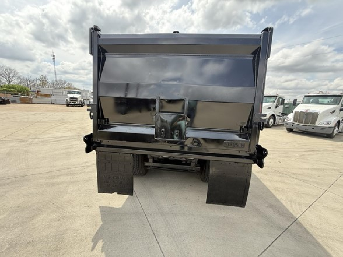 Dump truck bed of a 2019 Freightliner 122SD with shiny steel dump box and rear hitch, viewed from the back showing tailgate and mud flaps.