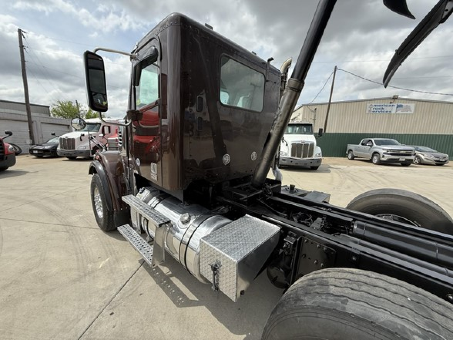 Truck cab and frame showing side fuel tank and chassis with cab door, Freightliner 122SD truck in view.