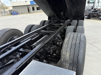Freightliner 122SD chassis with raised dump bed showing dual rear axles and hydraulic frame components.