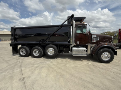 Dump truck side view showing a 2019 Freightliner 122SD with black dump body, chrome exhaust, and multiple rear axles.
