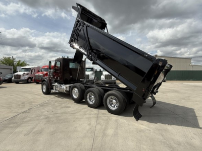 Freightliner 122SD dump truck in service showing raised dump bed and dual rear axles with black dump body and red cab.