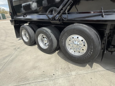 Wheel and tire arrangement on a Freightliner 122SD dump truck showing multiple silver rims and black undercarriage.