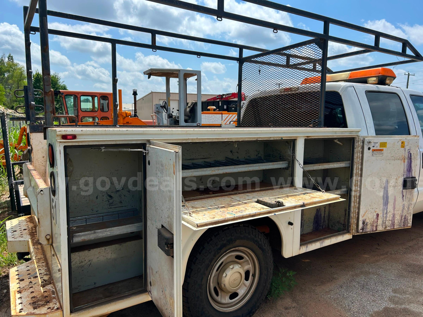 2016 Ford F250 service/utility truck bed with open compartments showing tool drawers and storage shelves; white cab with amber light bar; rust and wear on metal storage box; visible sign text on image watermark from govdeals.