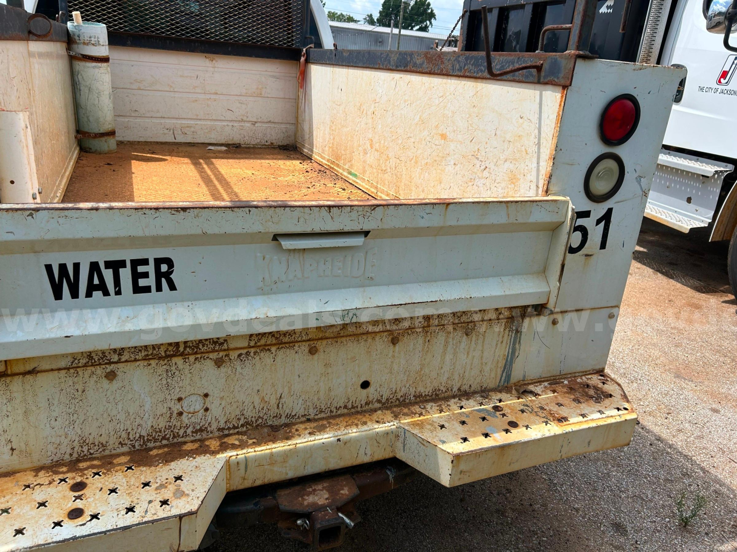 Truck bed of a used 2016 Ford F250 utility/service vehicle with rusted metal, WATER label on tailgate, and hydraulic components visible.
