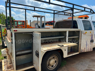 2016 Ford F250 service/utility truck bed with open compartments showing tool drawers and storage shelves; white cab with amber light bar; rust and wear on metal storage box; visible sign text on image watermark from govdeals.