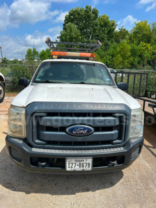Front view of a 2016 Ford F-250 Super Duty utility truck showing grille with Ford emblem, Texas license plate, roof rack, and light bar.