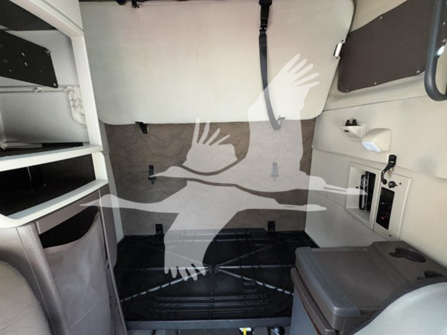Volvo VNL cabin interior view with sleeper area and storage shelves, vertical panels, and control panel; text and labels not legible.