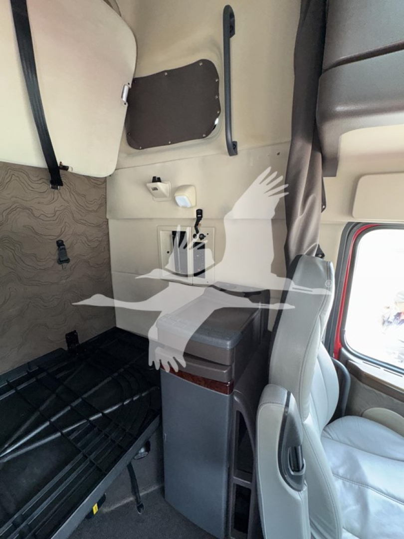 Truck cab interior showing side wall, storage cabinet, and seating in Volvo VNL 64T670 sleeper area.