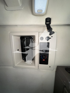 Table center console area of a Volvo truck cab with electrical outlet, control switches, and a plug-in power cord visible.