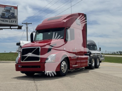 Volvo VNL64T670 sleeper truck in red, side view, with multiple axles and long hood.