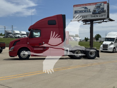 Volvo VNL 64T670 tractor (2018) in red, side view with sleeper cab, showing chrome wheels and tandem rear axles; dealership lot in background.