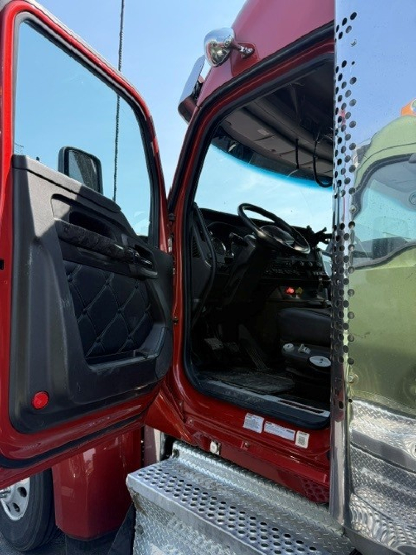 Kenworth W990 cab interior view through open door showing steering wheel, dashboard, and steps with chrome accents.