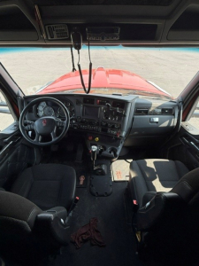 Kenworth W990 cab interior view from driver's seat showing dashboard with gauges, steering wheel, center console, gear shifter, and two seats.