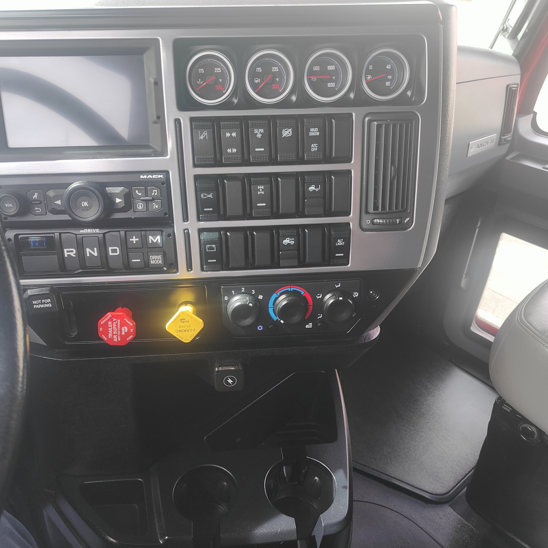 Dashboard and controls of a 2022 Mack AN64T70 sleeper truck showing instrument gauges, gear shifter area, climate controls, and push buttons.